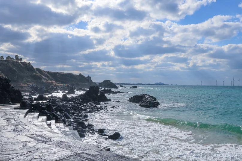 A rocky coastline with ocean waves and a cloudy sky, showing natural rock formations. - 済州島・涯月（エウォル）の海を飲み込む贅沢。韓屋と絶景が織りなす『ヘジゲ（海知開）』完全ガイド