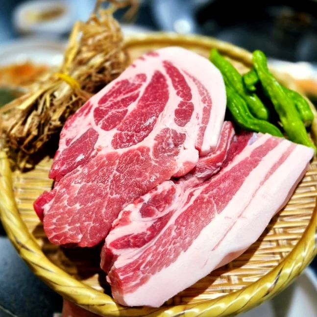 Slices of raw black pork and green chili peppers on a bamboo tray - 済州島・西帰浦で見つけた、至高の黒豚体験。麦わらの香りを纏う「Hwago(ファゴ)」の誘惑