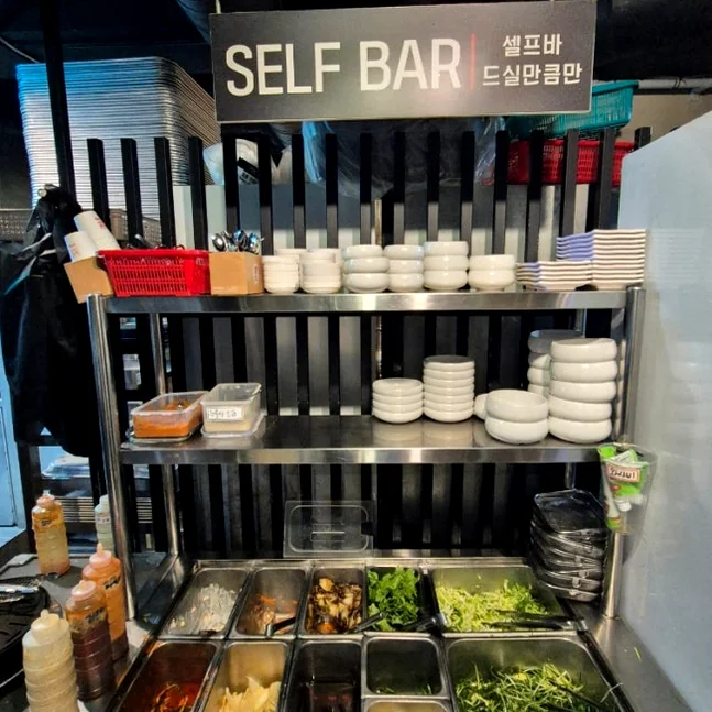 Stainless steel self-bar containing various side dishes and seasonings - 済州島・西帰浦で見つけた、至高の黒豚体験。麦わらの香りを纏う「Hwago(ファゴ)」の誘惑