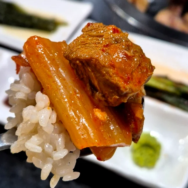 A spoonful of rice topped with grilled pork and red kimchi - 済州島・西帰浦で見つけた、至高の黒豚体験。麦わらの香りを纏う「Hwago(ファゴ)」の誘惑