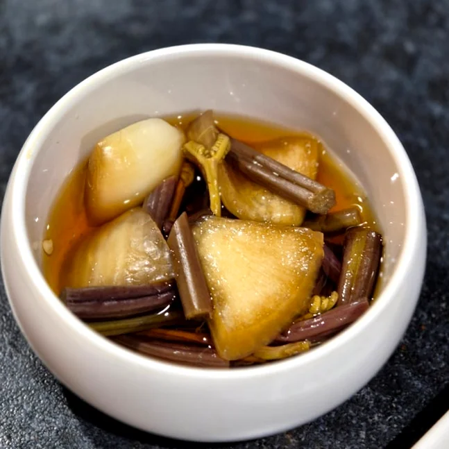 A small white bowl filled with pickled onions and vegetables - 済州島・西帰浦で見つけた、至高の黒豚体験。麦わらの香りを纏う「Hwago(ファゴ)」の誘惑