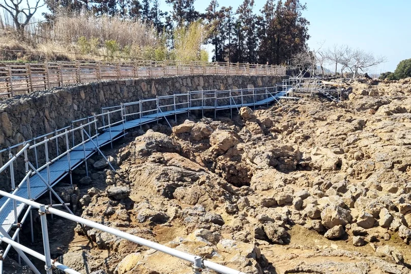 암벽 사이를 지나는 감각적인 산책로의 원경 - A Journey into Jeju's Volcanic Soul: Exploring the Pahoehoe Lava Field Park in Aewol