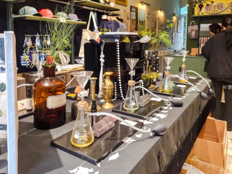 Scientific glass flasks and perfume bottles on a dark display table - 2026年ソウル・新堂洞(シンダンドン)で見つけた、パリの記憶。ライフスタイルショップ『セシル・アンド・セドリック(Cecile Cedric)』へ