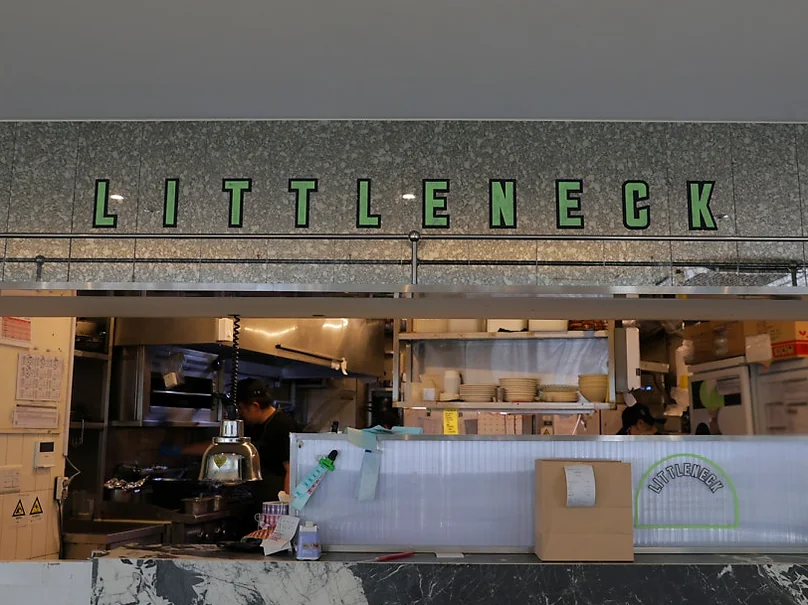 An interior view of a restaurant kitchen counter with a large 'LITTLENECK' sign on the wall. - 漢南洞のアイコン 'LITTLENECK' 完全攻略。プレミアムな週末ブランチと最新ショールーム巡り ✨