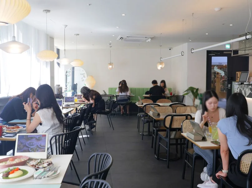 A wide interior view of a restaurant dining area with customers seated at tables. - 漢南洞のアイコン 'LITTLENECK' 完全攻略。プレミアムな週末ブランチと最新ショールーム巡り ✨