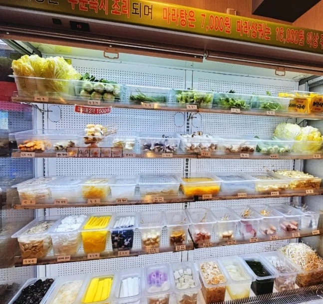 Multiple shelves in a refrigerator filled with containers of fresh vegetables and ingredients - ソウル・新堂洞の路地裏で見つけた、心まで満たされるシビ辛の聖地：新羅坊（シルラバン）マラタン