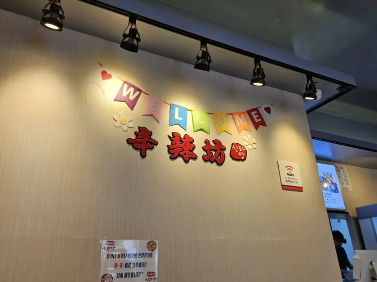 Wooden interior wall with brand name lettering and overhead track lighting - ソウル・新堂洞の路地裏で見つけた、心まで満たされるシビ辛の聖地：新羅坊（シルラバン）マラタン