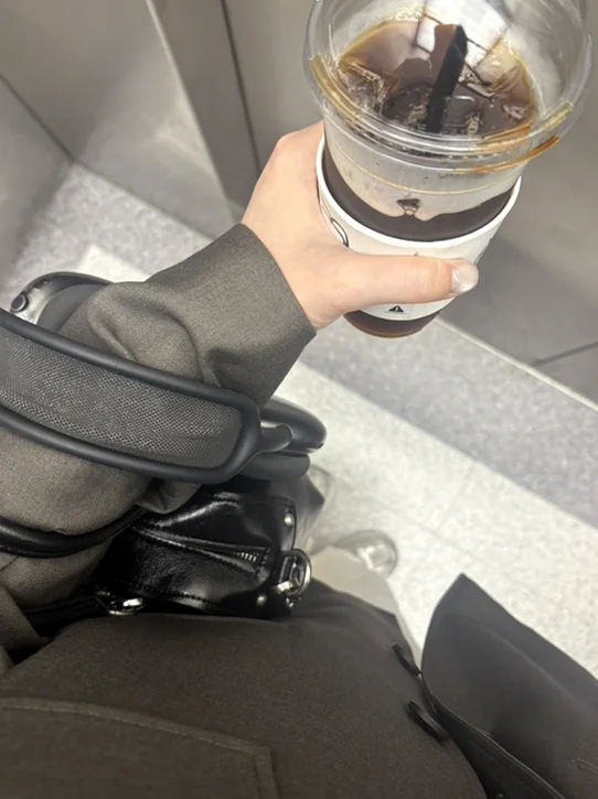 Iced coffee in a plastic cup held above a black handbag - 春のソウル、漢南洞（ハンナムドン）で見つける旬の『K-Fashion』と洗練された日常の楽しみ方