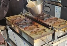 Person pouring liquid batter into fish-shaped molds on a Mochi Taiyaki machine. - A Masterclass in Gluten-Free Snacking: Mochi Taiyaki at Mojjibangatgan Yeonnam
