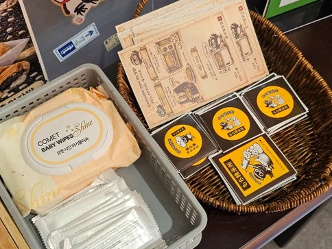 Basket containing branding coasters and flyers, next to a container of wet wipes and utensils on a counter. - A Masterclass in Gluten-Free Snacking: Mochi Taiyaki at Mojjibangatgan Yeonnam