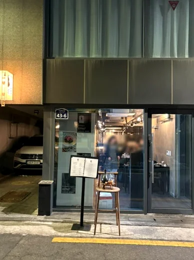 Exterior of the restaurant at night with glass doors and a menu stand - 2026年ソウル・新堂洞の最旬スポット。伝統酒ソムリエが贈る至福の韓食ダイニング『ピョジュ(表酒)』へ。