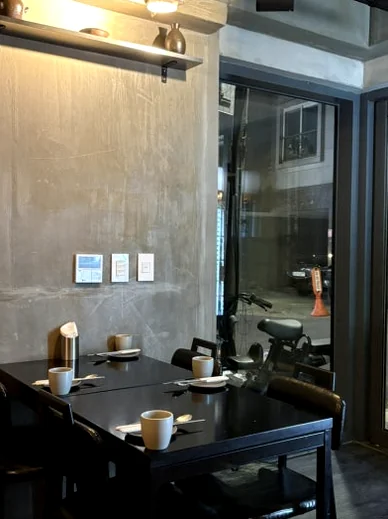 A black wooden table with two white cups and a small dish against a concrete wall - 2026年ソウル・新堂洞の最旬スポット。伝統酒ソムリエが贈る至福の韓食ダイニング『ピョジュ(表酒)』へ。