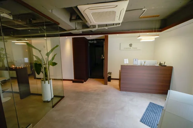 Modern reception area with a wooden desk and a tall green plant - ソウル新堂洞(シンダンドン)で見つける極上タイマッサージ:カシアタイでの癒し体験 ✨