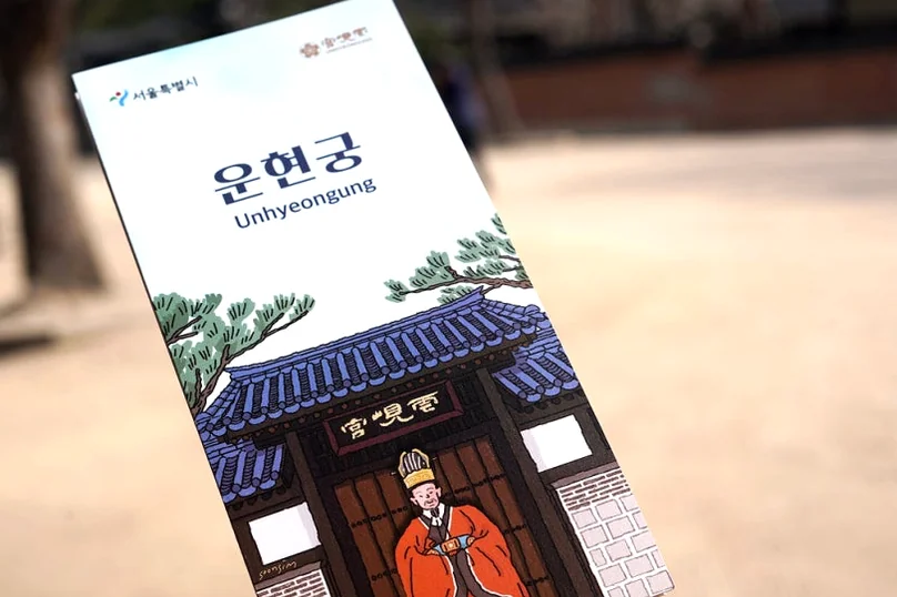 White paper brochure with the text Unhyeongung held in front of a blurred background - 麗しき「雲峴宮（ウニョングン）」で辿る、朝鮮王朝の残り香と春の静寂