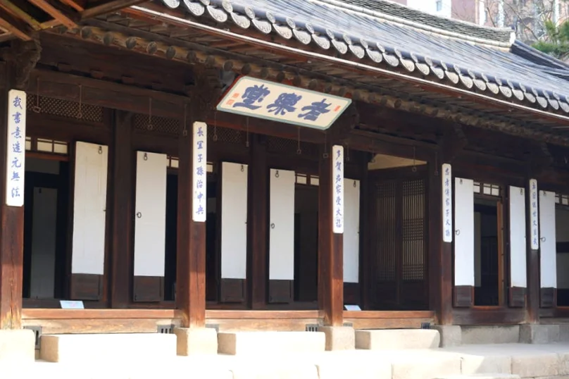 Exterior of a wooden building with a horizontal plaque and white paper panels on doors - 麗しき「雲峴宮（ウニョングン）」で辿る、朝鮮王朝の残り香と春の静寂