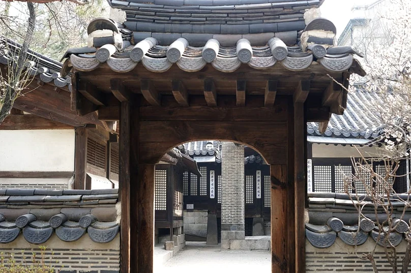 Small wooden gate with a tiled roof framed by stone and brick walls - 麗しき「雲峴宮（ウニョングン）」で辿る、朝鮮王朝の残り香と春の静寂