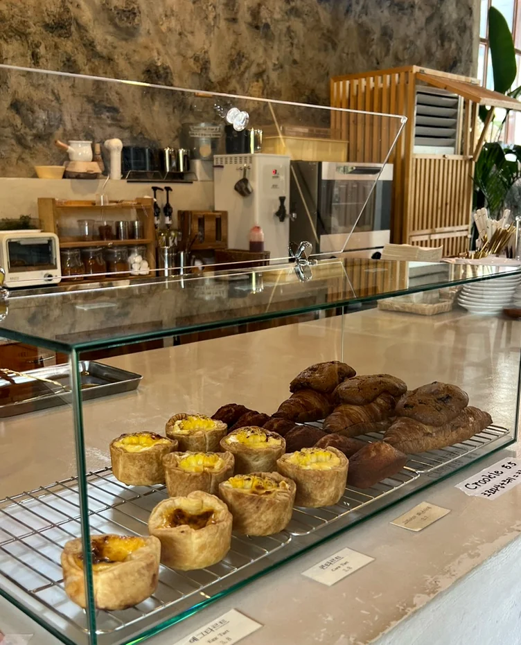 Egg tarts and pastries displayed inside a glass case on a counter - 済州島・涯月(エウォル)の静かな休息地。ミッカン倉庫(Mikkang Changgo)で過ごす、蜜柑の香りに包まれた休日