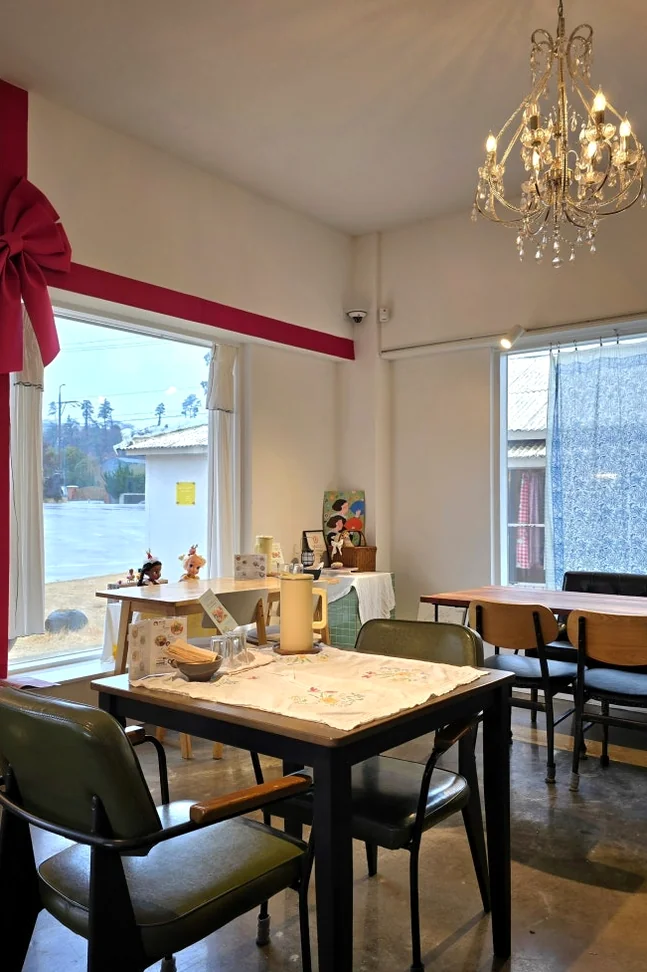A cafe interior with a chandelier and a large pink ribbon decoration on the window - 済州島・涯月(エウォル)の静かな休息地。ミッカン倉庫(Mikkang Changgo)で過ごす、蜜柑の香りに包まれた休日