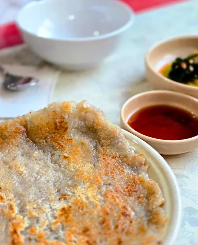 A harmonious meal arrangement with a golden-brown potato pancake, neat side dishes, and a soy sauce dipping bowl - Samcheongdong Sujebi: A Michelin-Recognized Taste of Traditional Korean Hand-Pulled Dough Soup in Seoul