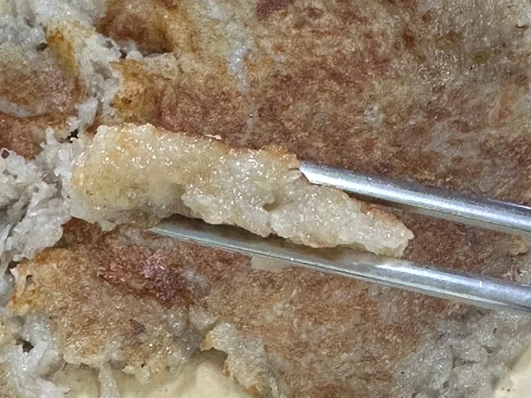 A pair of chopsticks lifting a piece of potato pancake - Samcheongdong Sujebi: A Michelin-Recognized Taste of Traditional Korean Hand-Pulled Dough Soup in Seoul