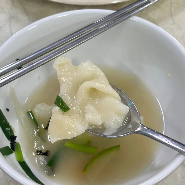 A close-up of sujebi being spooned from a white bowl, showcasing the warm, comforting dish - Samcheongdong Sujebi: A Michelin-Recognized Taste of Traditional Korean Hand-Pulled Dough Soup in Seoul