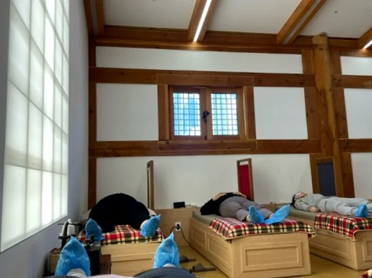 좌훈 체험을 하고 있는 방문객들의 뒷모습. 건강과 관련된 문화 체험의 한 장면으로 자연스럽게 연출되었습니다. - ソウル薬令市韓医学博物館：五感で巡る、韓国伝統医療の魅力と癒し体験🌿