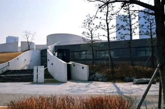 The exterior of a modern, curved building with trees. - 仁川 松島：世界の文字を巡る旅へ！国立世界文字博物館で知的好奇心を刺激する一日を