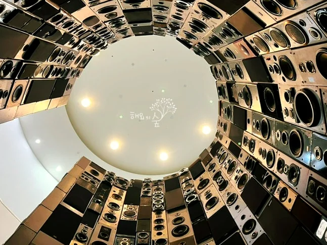 An upward view into a circular art installation made of speakers. - 仁川 松島：世界の文字を巡る旅へ！国立世界文字博物館で知的好奇心を刺激する一日を