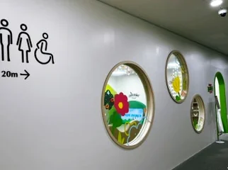 A white hallway with multiple circular windows and a restroom sign. - 仁川 松島：世界の文字を巡る旅へ！国立世界文字博物館で知的好奇心を刺激する一日を