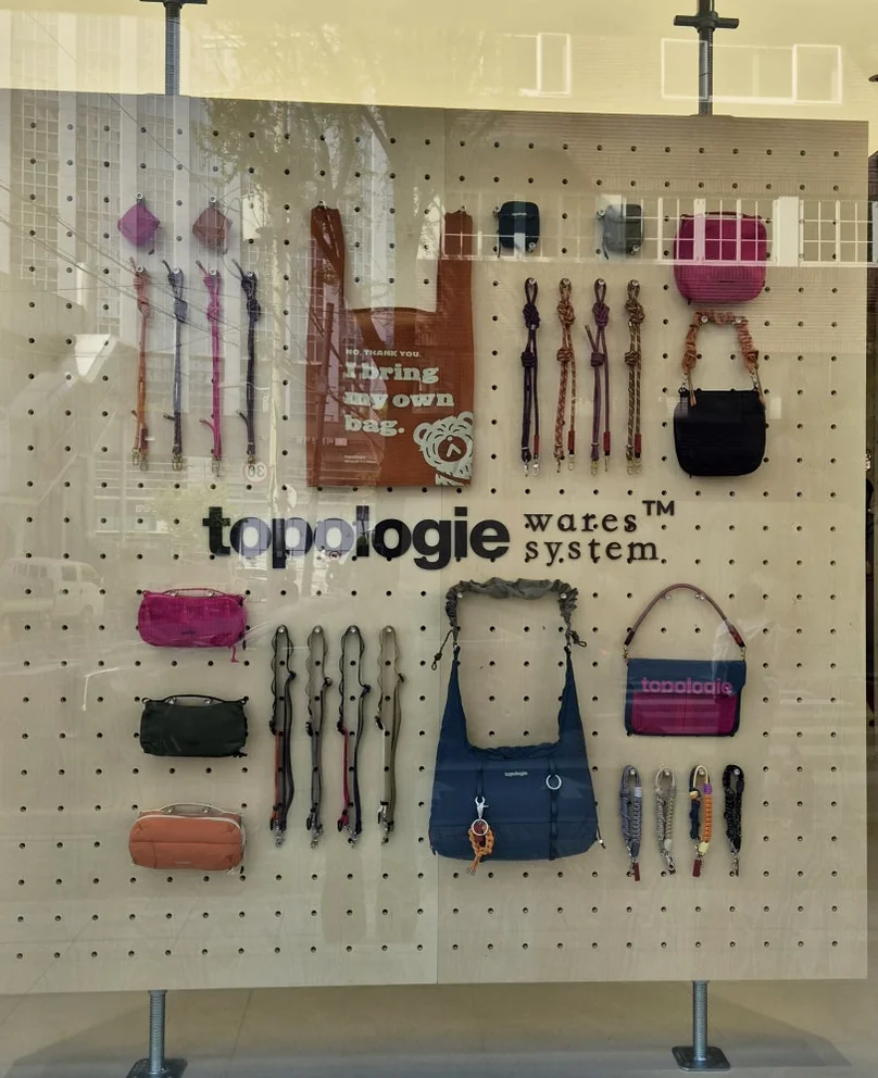 Window display featuring 'topologie wuses™ system' with a variety of small bags and accessories - ソウルの森に誕生した Topologie 韓国初フラッグシップ：2026 SS ‘The Starbound’ の世界 🧭