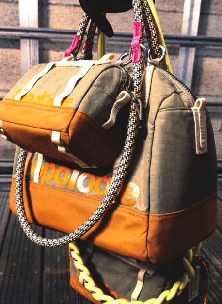 Close-up of two Topologie bags, one brown and one green, hanging with prominent rope straps - ソウルの森に誕生した Topologie 韓国初フラッグシップ：2026 SS ‘The Starbound’ の世界 🧭