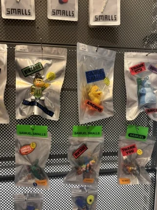 Small figurines in plastic bags hanging on a pegboard with Samuel Smalls labels - A Masterclass in Mid-Century Curation: Navigating Samuel Smalls Seongsu Flagship