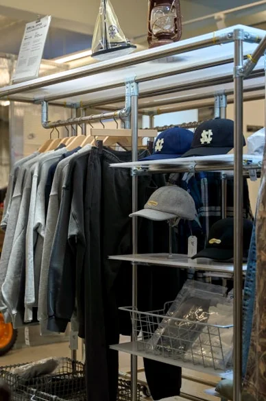 Metal shelving unit displaying navy caps and folded apparel - 26SS Nautica Guide: Navigating the Hype Logistics at Worldwide Seoul Seongsu