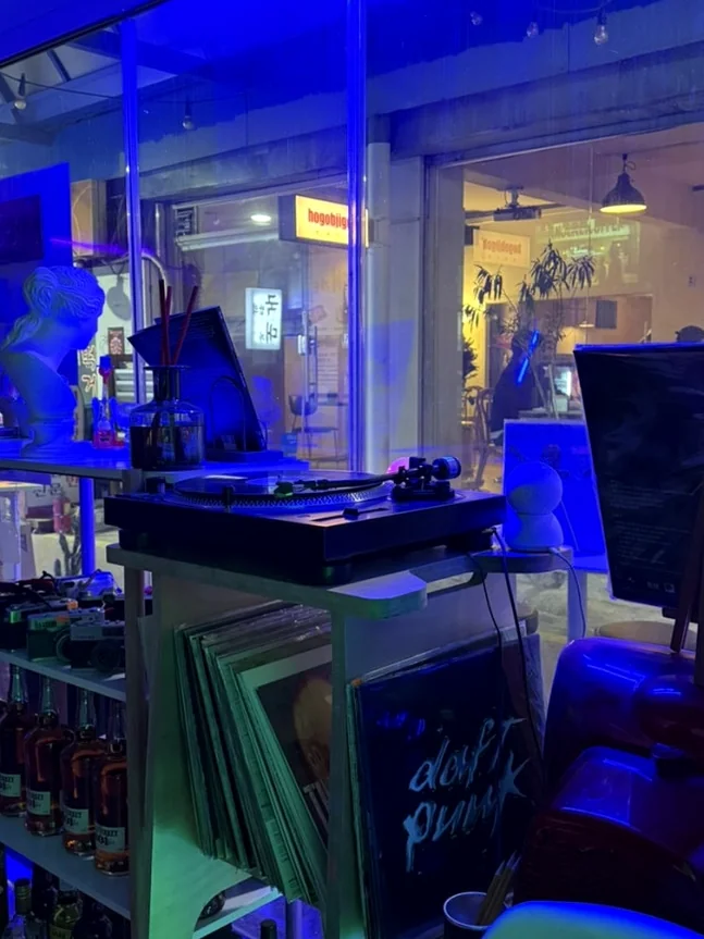 Interior with a DJ setup, vinyl records, and bottles under blue neon light. - A Cinematic Escape in Seongsu: The Deep Vibe Guide to Kumgyol Wine & LP Bar