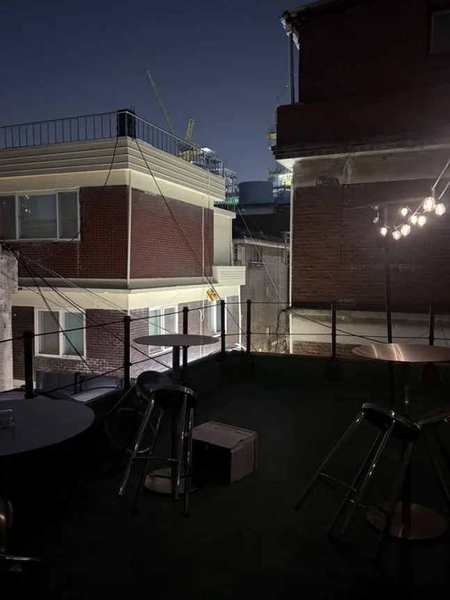 Rooftop seating area at night with string lights and surrounding buildings. - A Cinematic Escape in Seongsu: The Deep Vibe Guide to Kumgyol Wine & LP Bar