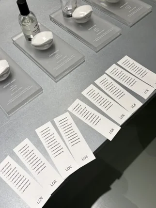 일렬로 놓인 하얀색 향수 시향지들과 진열된 향수병 - Beyond Scent: A Deep Dive into LOE Seongsu Flagship Store’s Vegan Fragrance Journey