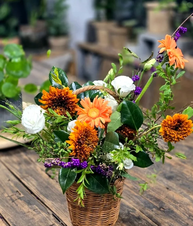 A flower basket with orange and white gerberas on a wooden table - A Curator's Guide to Atelier Tium: Elevating Floral Artistry in Yeonhui-dong