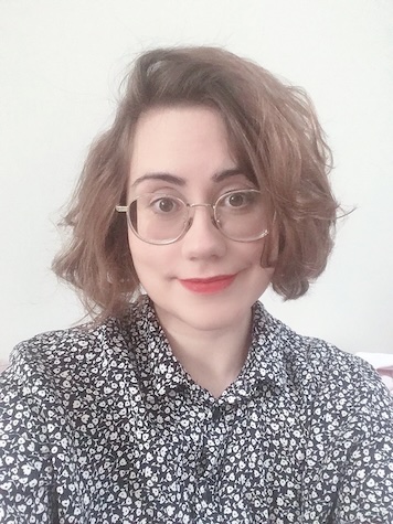 Photo of Emma Winston, a woman with dark hair and glasses wearing a floral shirt and smiling at the camera
