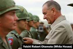 Johnson awards the Distinguished Service Cross to First Lieutenant Marty A. Hammer, in Vietnam. 约翰逊在越南向中尉马蒂·A·汉默颁发铜十字英勇勋章。