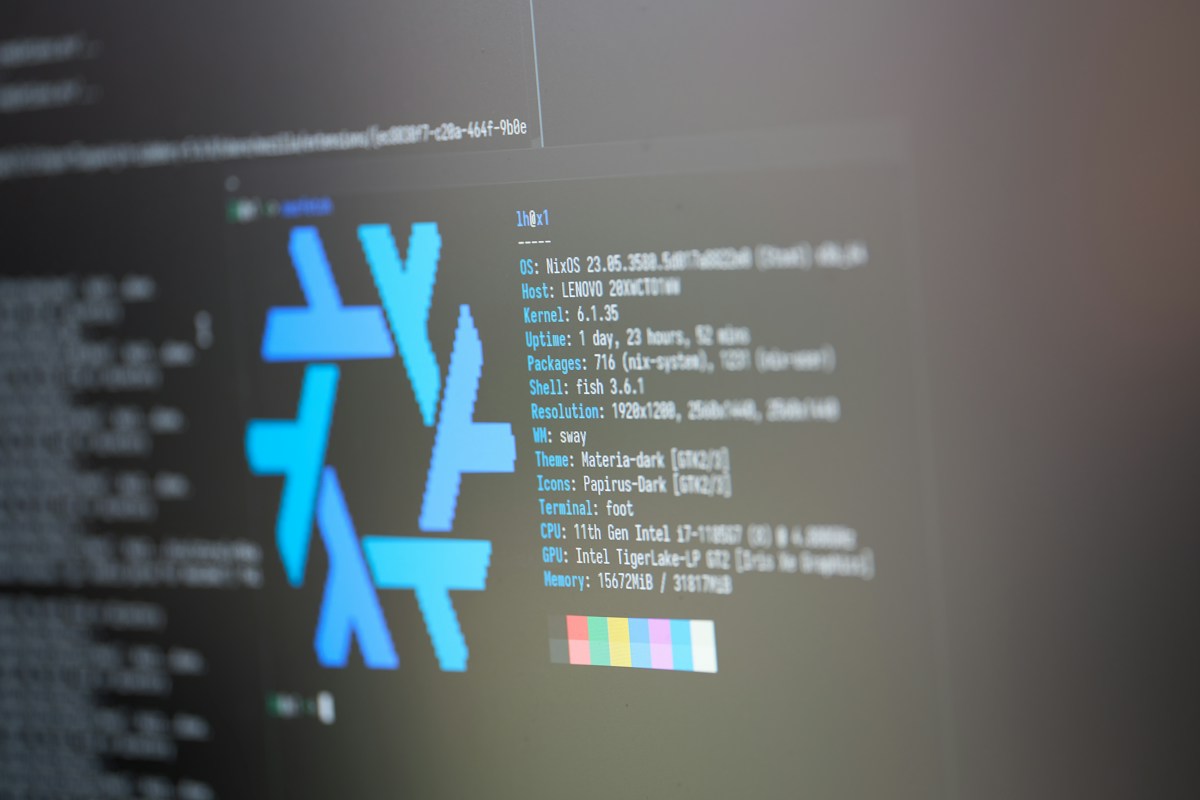 Close-up of a monitor showing a Linux terminal with NixOS system info output and a shell prompt