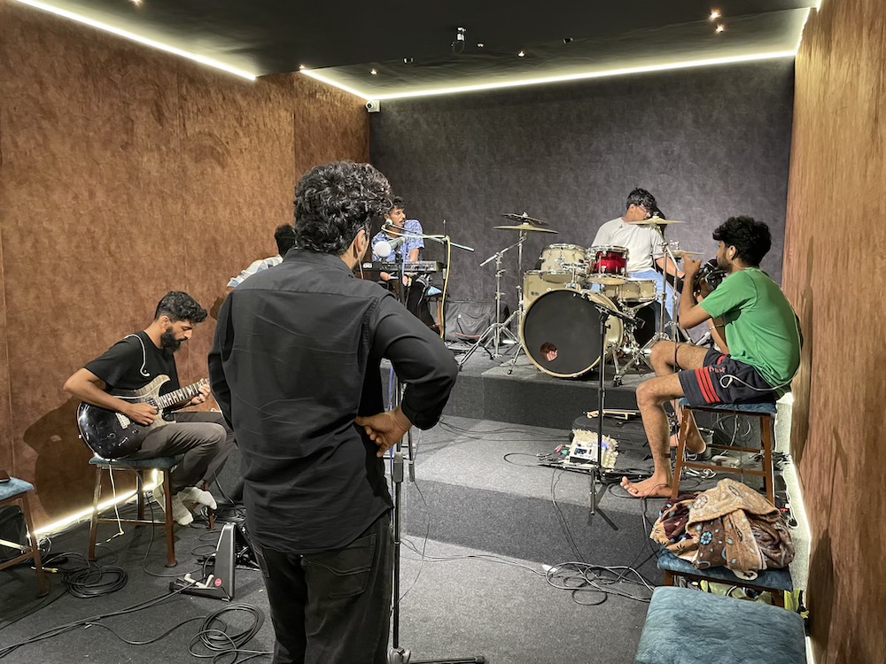 Players between takes, guitars and drums set up around the room