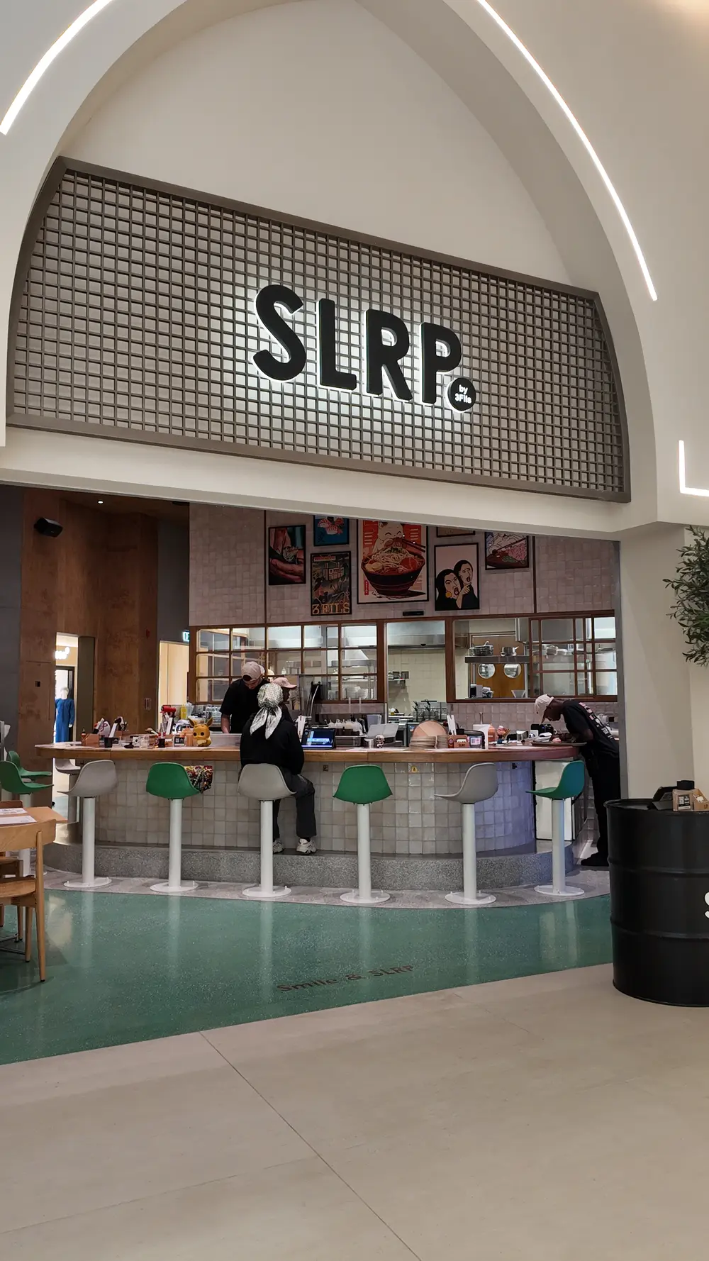 "DJI image: Close-up of modern, sleek interior design, featuring a luxurious beige sofa, vivid orange pendant lamp, and large, framed, abstract art."