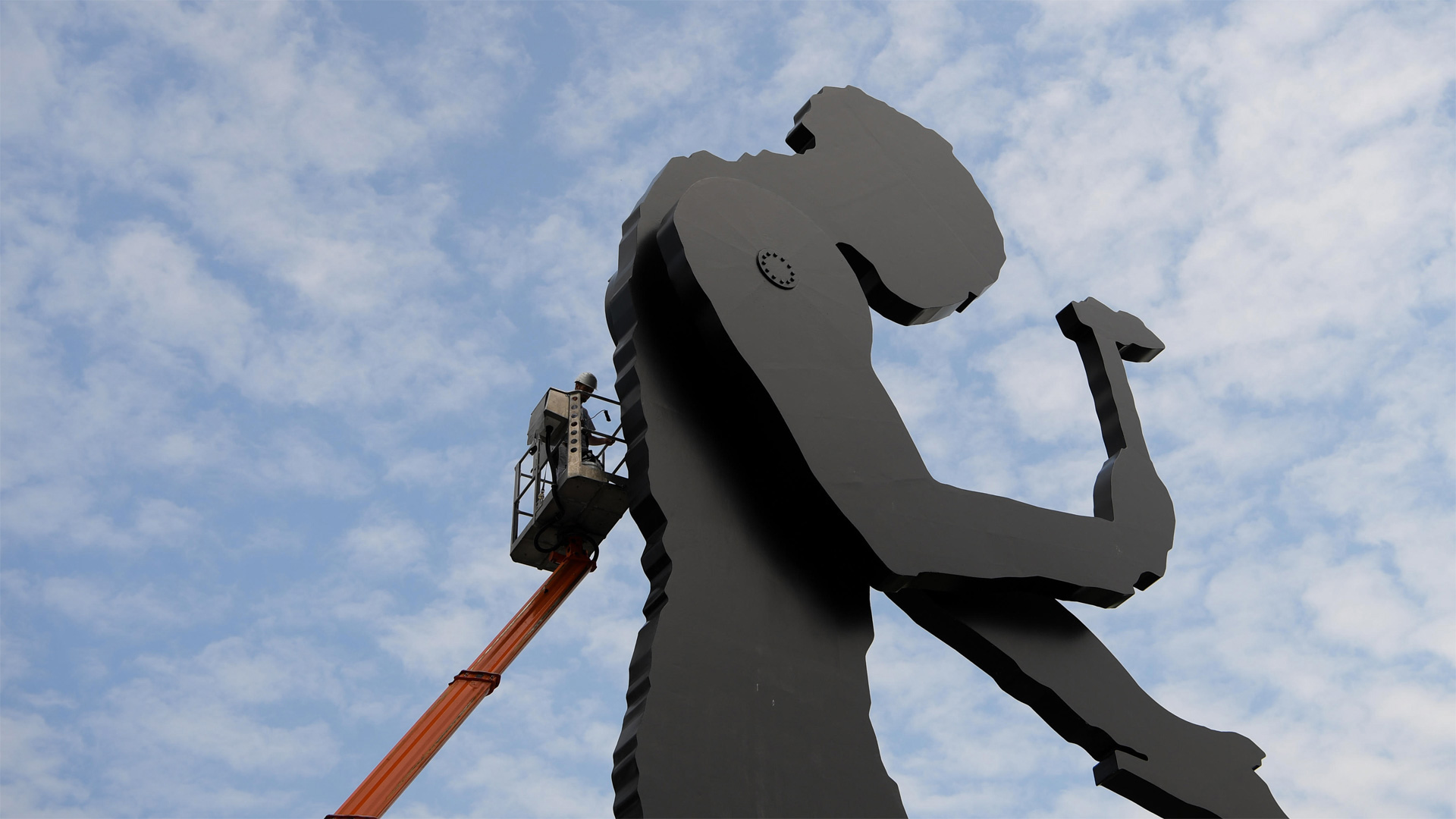 A worker painting the Hammering Man, a sculpture by Jonathan Borofsky, in Frankfurt, Germany - Arne Dedert/Alamy)