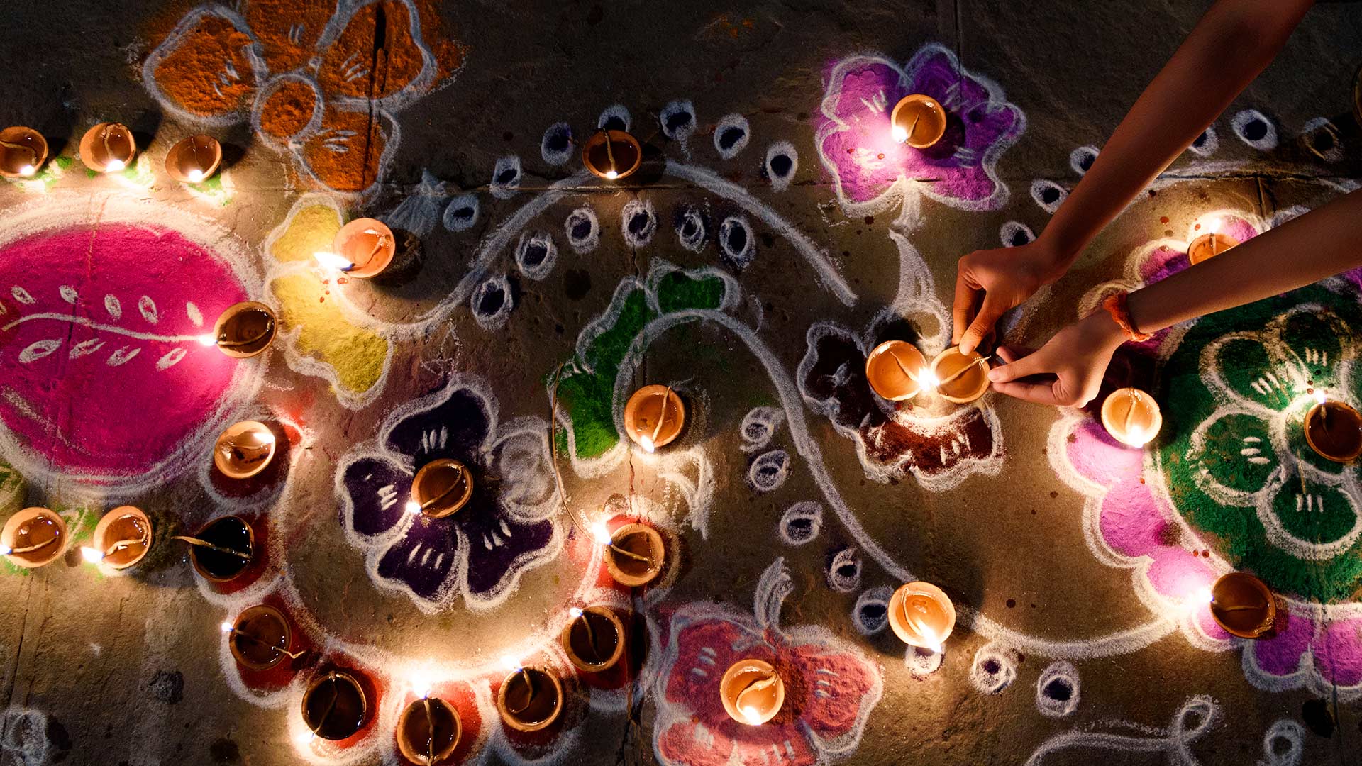 Oil lamps being arranged on rangoli designs during Diwali - Subir Basak/Getty Images)