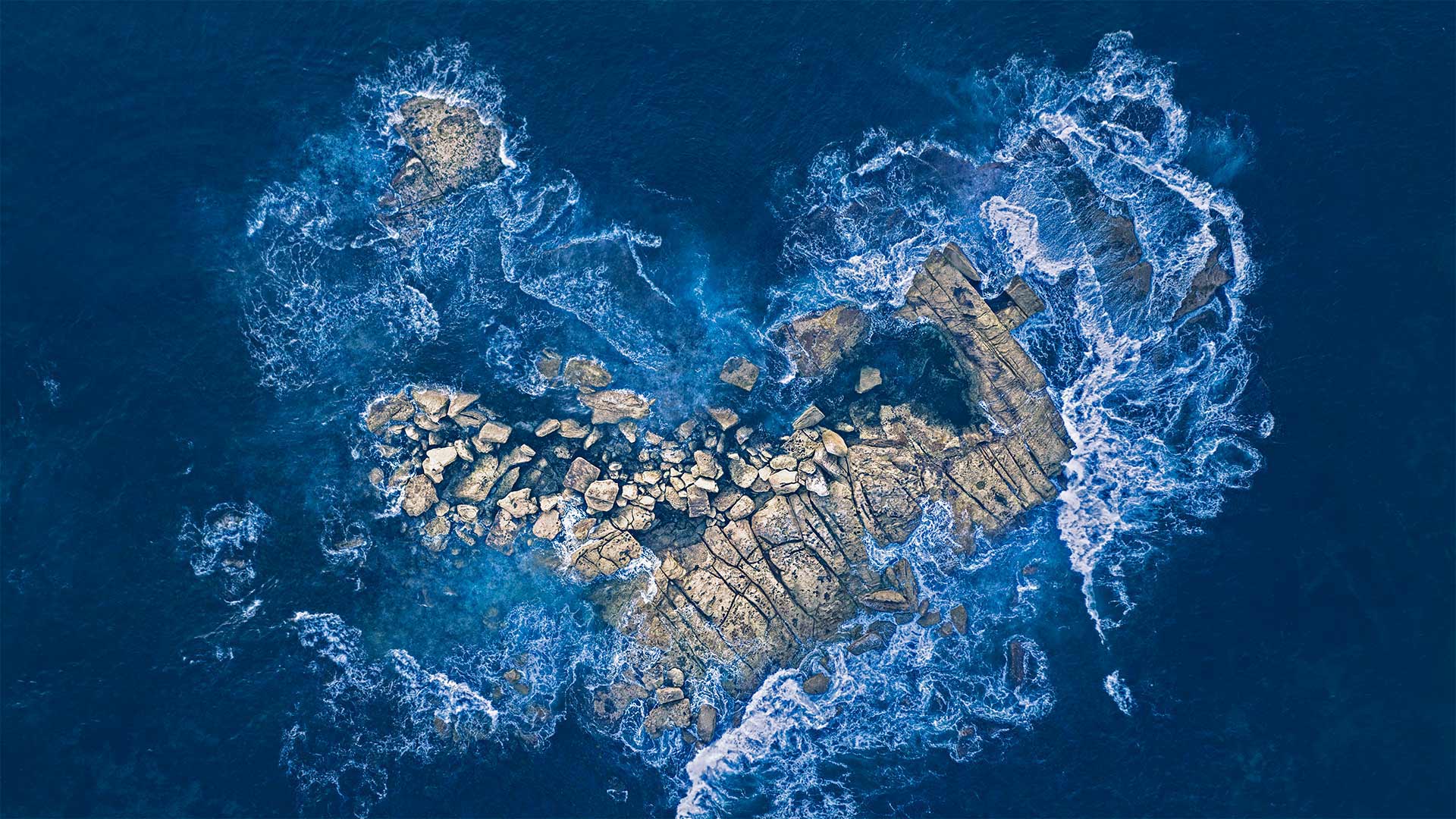 Ocean waves crashing over a heart-shaped rock island off the coast of Sydney, Australia - Kristian Bell/Getty Images)
