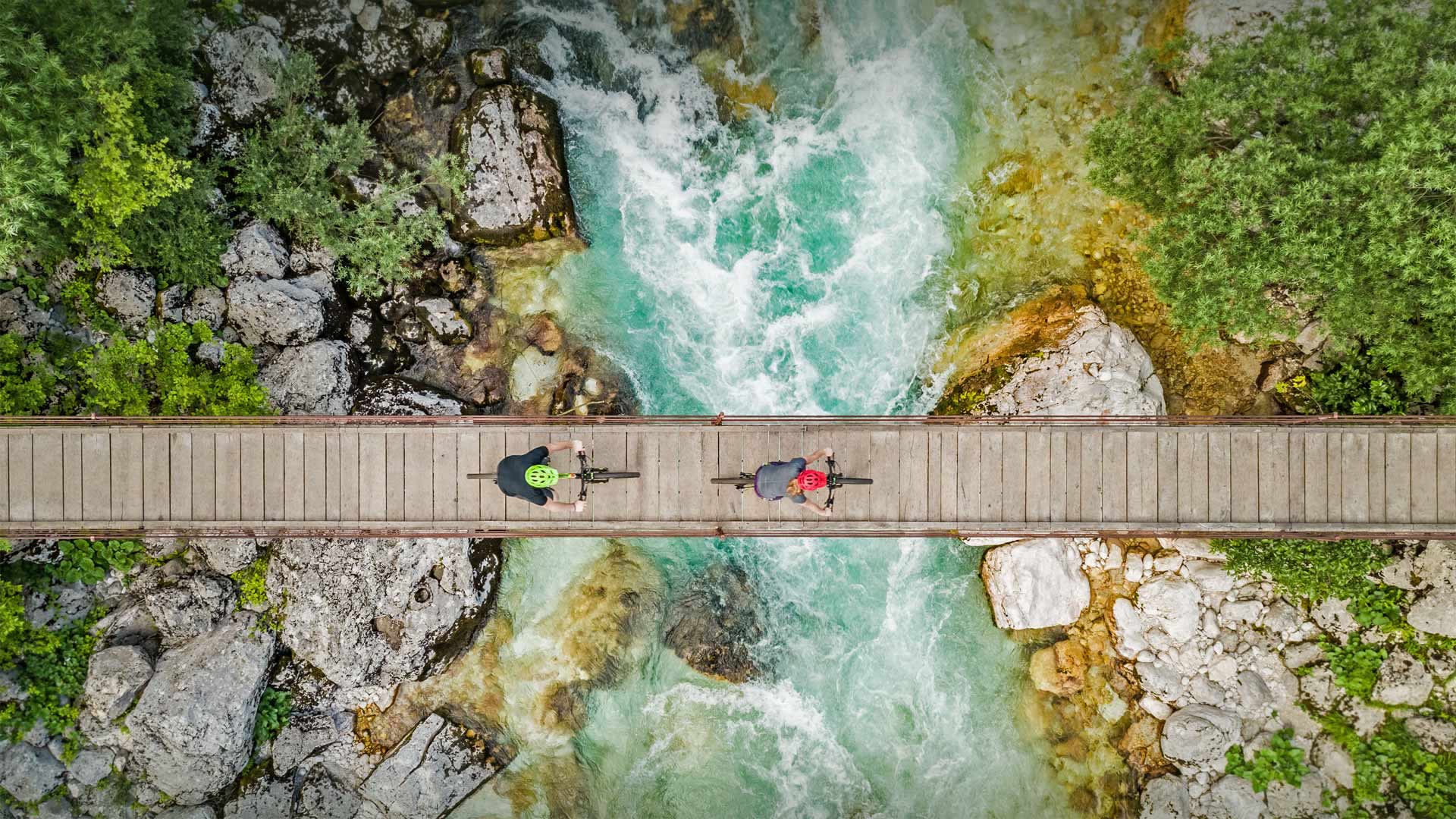 Cyclists on a wooden suspension bridge over the Soča River in Slovenia - Amazing Aerial Agency/Offset by Shutterstock)