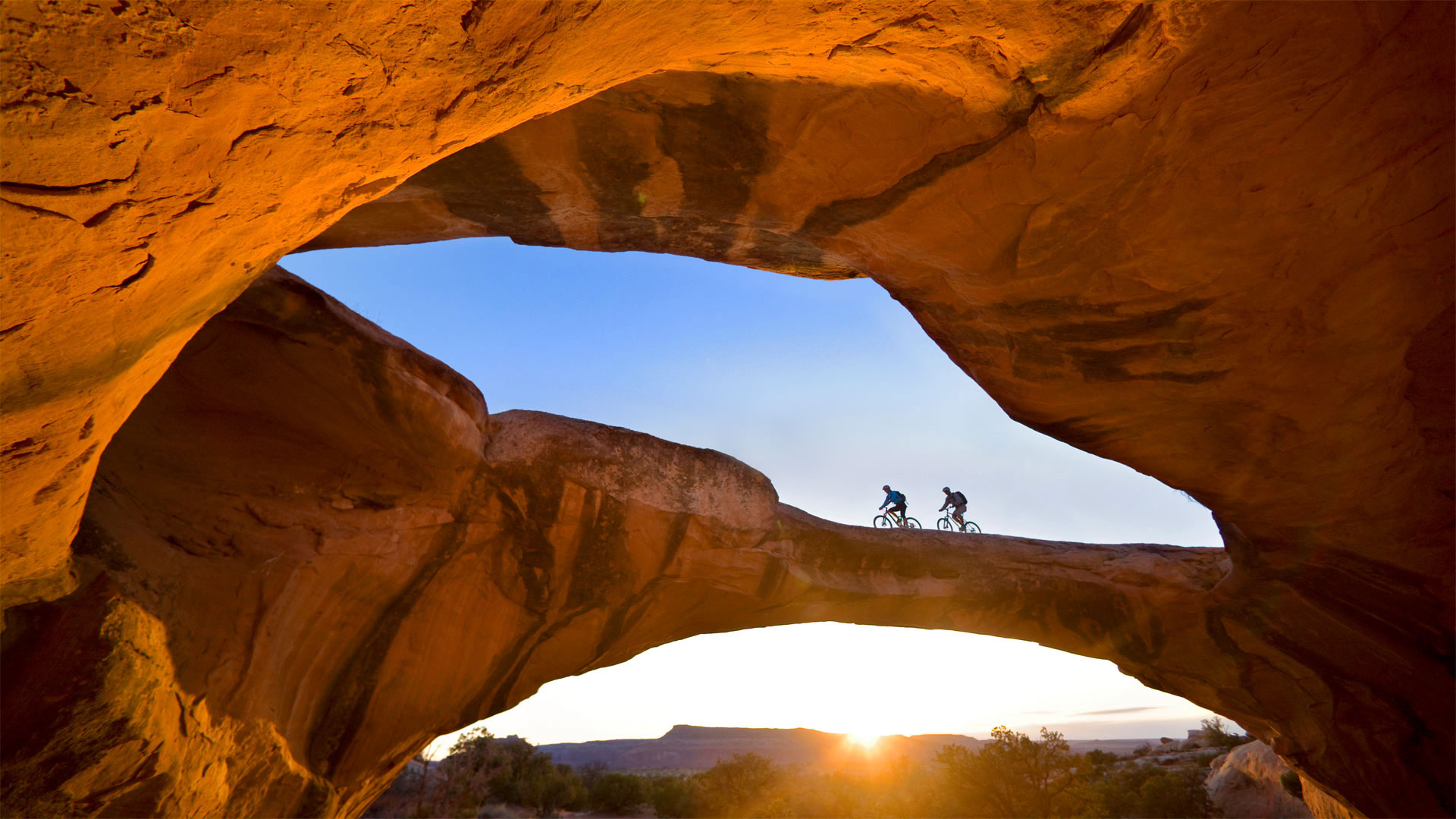 Cycling across a natural rock arch in the desert near Moab, Utah - Whit Richardson/Cavan)