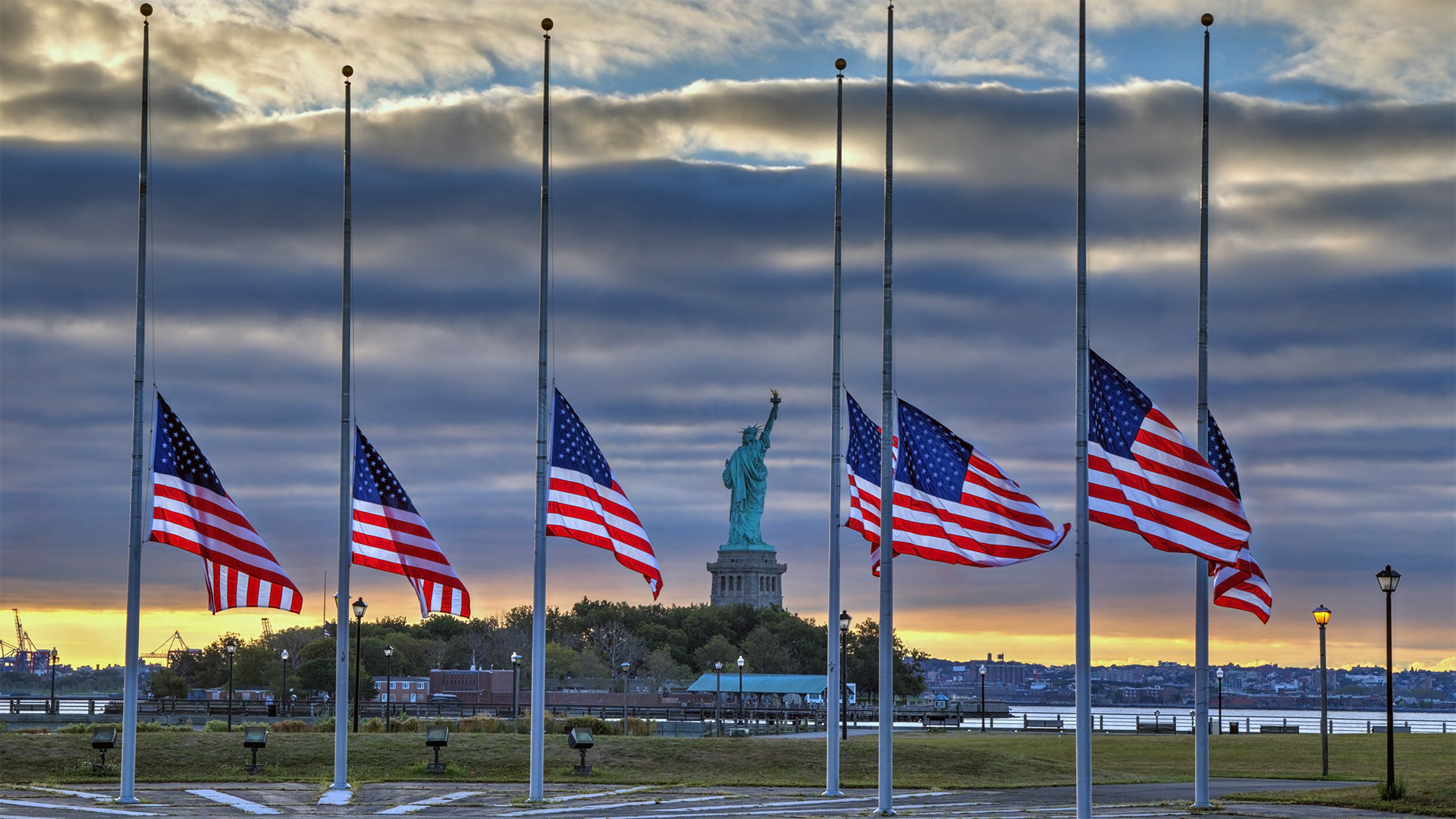 Statue of Liberty seen behind US flags at half-staff for the anniversary of September 11 in 2014, New York City - Adam Parent/Shutterstock)