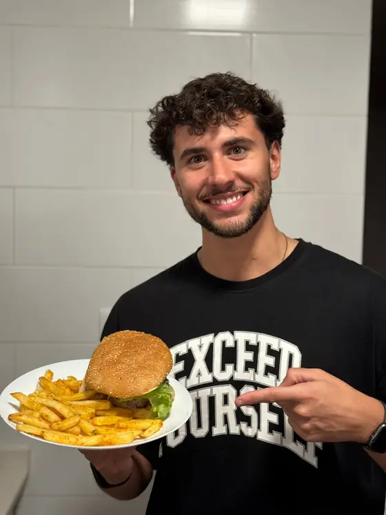 Treinador da Step One a sorrir com um prato de hambúrguer e batatas