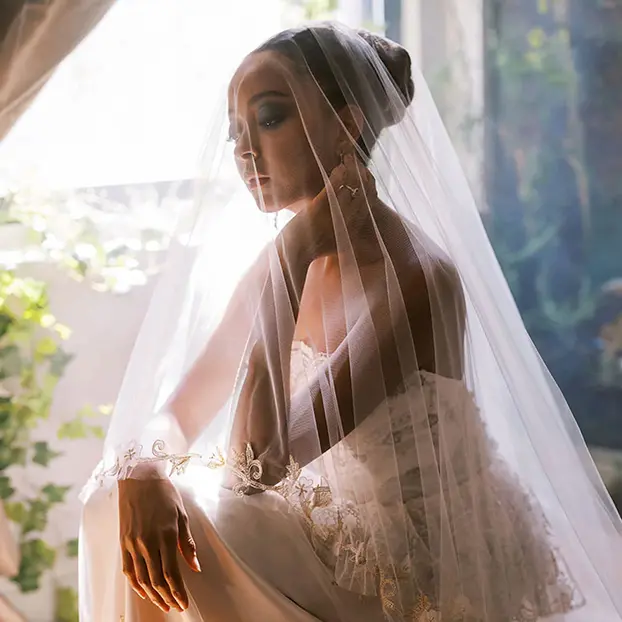 Une femme africaine avec un chignon haut élégant et une voile de mariée.